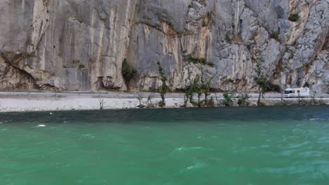 A-car-drives-along-the-riverbank-of-the-Cetina-River-in-Omis,-Croatia