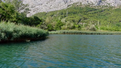 Handheld-shot-displaying-the-River-Cetina-and-surrounding-mountains-in-Omis,-Croatia,-featuring-a-panoramic-view-and-lush-greenery