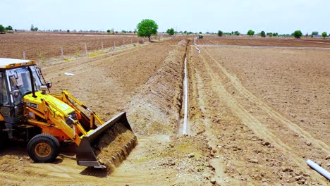Aerial-view,-Front-view-of-Earthmoving-machine-cover-up-Underground-water-pipeline-with-soil-in-India