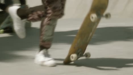 Skateboarder-in-camo-pants-running-and-dropping-board,-jumps-on-to-ride