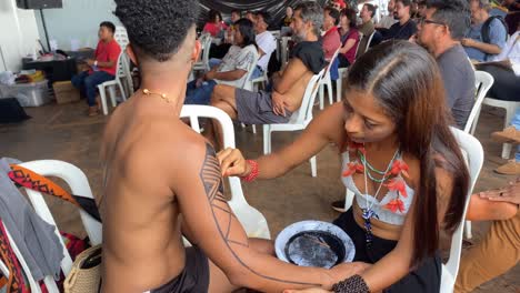 A-beautiful-Amazon-lady-applies-the-black-traditional-drawing-to-a-man