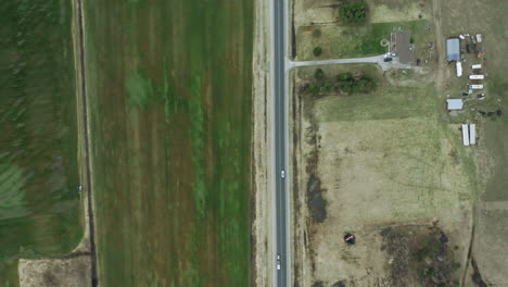 Very-high-aerial-shot-of-thin-country-road-with-farm-land-on-either-side