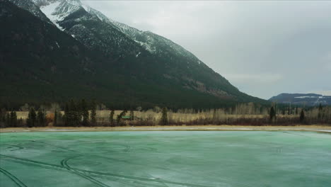 Vibrant-bright-teal-water-in-lake-at-the-foothill-of-snow-capped-mountains