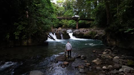 Man-jumping-rocks-in-tropical-river-banks-in-Costa-Rica's-jungle