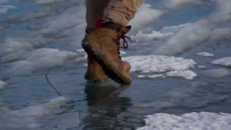 Slow-motion-shot-of-the-boots-of-a-person-walking-on-ice