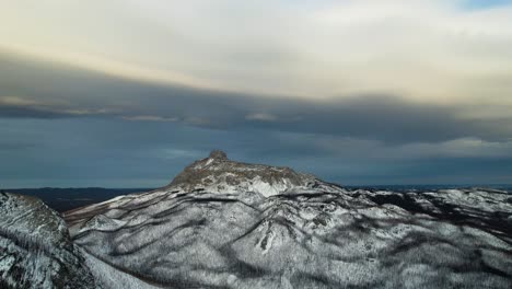 Drone-gimbal-down-revealing-the-snowy-slope-of-a-giant-mountain-in-Rocky-Mountains,-Alberta