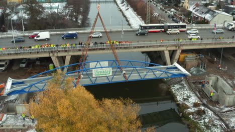 Construction-workers-watching-lowering-of-bridge-onto-concrete-pillars