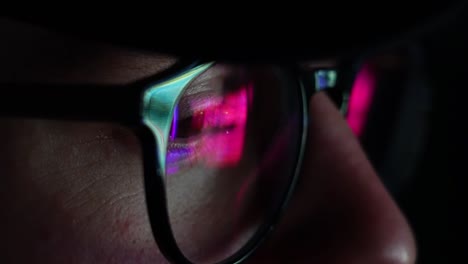 Man-on-his-computer-at-night-ultra-violet-blue-light-hitting-glasses---closeup-steady-shot