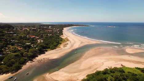 Aerial-drone-view-of-an-estuary-flowing-into-the-sea-at-Las-Baulas-National-Marine-Park,-Costa-Rica-shoreline