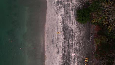 Aerial-drone-view-of-a-girl-lying-in-seashore-in-a-tropical,-hidden-and-exotic-beach-of-Costa-Rica