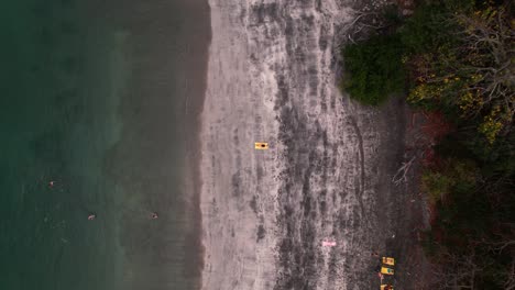 Vista-Aérea-De-Una-Niña-Tumbada-En-La-Orilla-Del-Mar-En-Una-Playa-Tropical,-Escondida-Y-Exótica-De-Costa-Rica