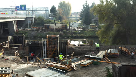 Construction-workers-walking-around-dredging-site-on-city-river-shore