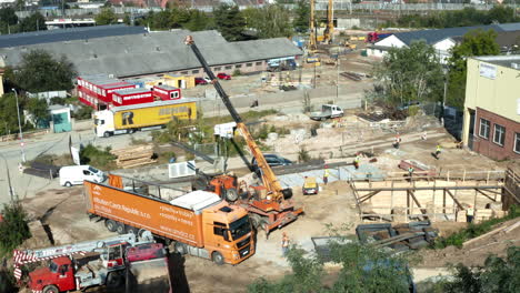 Mobile-crane-moving-steel-beam-from-freight-truck-at-construction-site