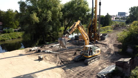 Bagger-Mit-Angehobener-Hydraulischer-Schaufel-Fährt-An-Flussbaggerstelle