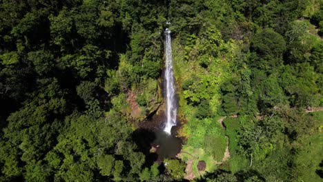 Drone-aerial-view-of-Viento-Fresco-flowing-waterfall-in-the-middle-of-humid-jungle-vegetation,-Monteverde