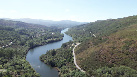 Aerial-shot-of-a-calm-river-flowing-through-a-valley-leading-up-to-a-mountain-in-Peneda-Geres-National-Park-in-Portugal