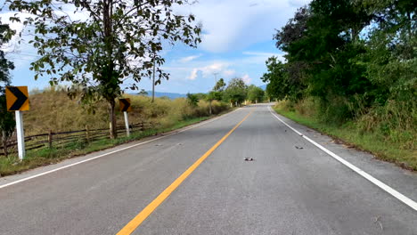Vista-Desde-La-Parte-Trasera-De-Un-Vehículo-A-Toda-Velocidad-A-Lo-Largo-De-Una-Carretera-Vacía-En-La-Provincia-Nan-De-Tailandia