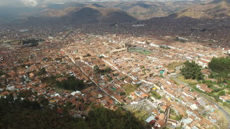 Aerial-Drone-View-of-Cusco,-Peru-on-a-beatiful-sunny-day-with-mountain-in-the-background