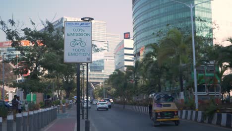 Smart-roads-in-smart-city-with-emission-signage-board,-smooth-city-road-traffic-flow,-new-India-financial-and-residential-complex-Bandra-Kurla-Complex-skyline-buildings-in-view