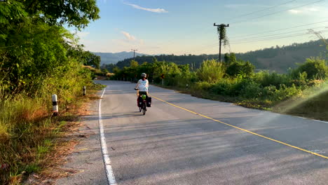 Eine-Einsame-Radfahrerin-Fährt-Auf-Einer-Leeren-Landstraße-In-Der-Nähe-Des-Fischerdorfes-Paknai-Im-Distrikt-Na-Muen,-Nan,-Thailand