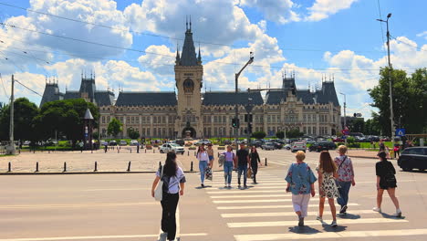 Pedestrians-crossing-road-in-front-of-Iași-Palace-of-Culture,-Romania