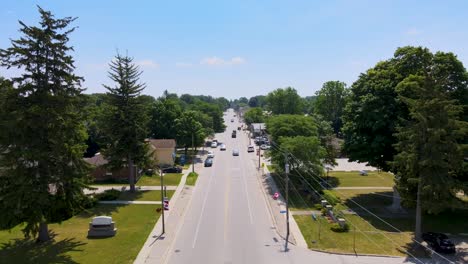 Drone-flying-over-cars-down-a-street-in-Mount-Brydges,-Ontario