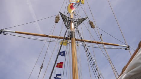 Looking-up-at-the-mast-of-a-sailing-vessel-against-a-blue-sky-background