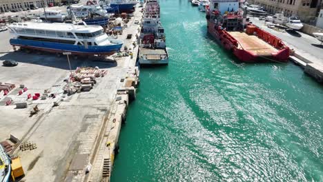 Drone-aerial-shot-over-and-towards-several-ships-in-a-boat-yard-including-a-red-tug-boat