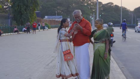 Älteres-Ehepaar-Mit-Seiner-Enkelin,-Die-Auf-Ihr-Smartphone-Schaut,-Um-Angeklickte-Bilder-Zu-überprüfen,-Lächelnd-Und-Glücklicher-Moment,-Chennai
