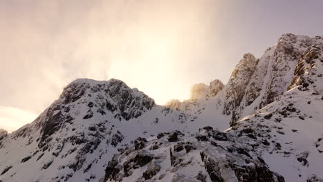 Inspirational-sunrise-aerial-view-over-snowy-jagged-arctic-mountains,-Lofoten