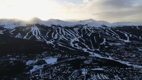 Aerial-Cinematic-drone-view-of-Breckenridge-Ski-area-and-town-from-Boreas-Pass-late-afternoon-sunset-over-mountain-tops-mid-winter-backwards-movement-pan-reveal