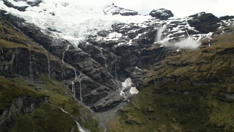 Majestic-Mount-Earnslaw-and-glacier-melting-into-hundred-waterfalls-to-valley---birds-eye-view