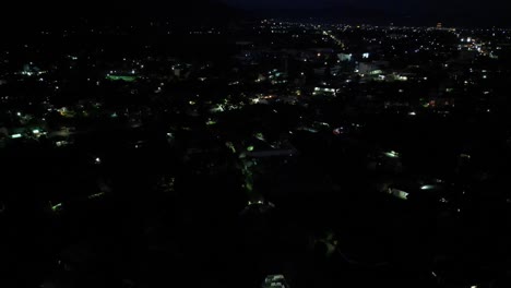 Vista-Aérea-Ascendente-De-Las-Luces-Nocturnas-En-Una-Pequeña-Ciudad-Provincial-Filipina-Desarrollada