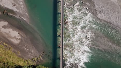 Aerial---narrow-bridge-over-shallow-green-river