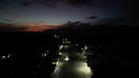 Overhead-drone-shot-of-busy-roads-of-a-small-Philippine-village-town-with-stunning,-orange-skyline-and-cloudscape