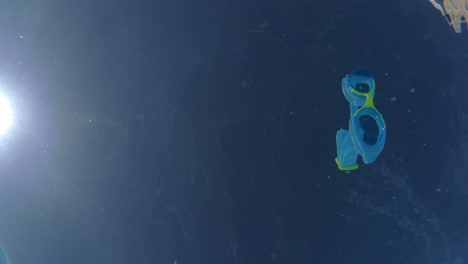 Vista-Submarina-De-Gafas-De-Natación-Arrojadas-A-La-Piscina,-Bengala-De-Rayos-De-Sol