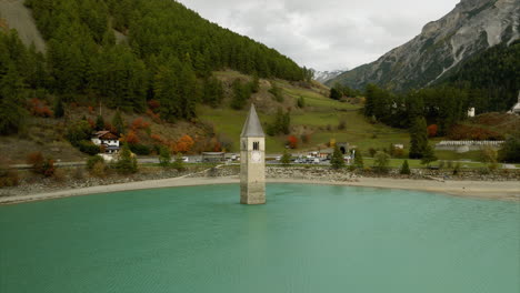Stunning-aerial-orbit-of-sunken-bell-tower-in-the-middle-of-idyllic-Lake-Resia-during-summer