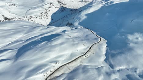 The-edge-of-Vikafjell-mountain-and-steep-curvy-road-leading-down-to-Myrkdalen-and-Voss-from-mountain-road-crossing-Vikafjell---Western-Norway-winter-aerial