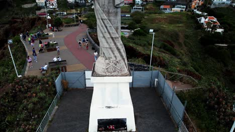 Aerial-view-rising-above-giant-Cristo-Rei-sculpture-sightseeing-landmark-on-the-Portuguese-coastline-of-Ponta-Garajau