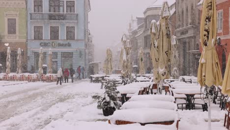 People-Walking-In-The-Street-During-Heavy-Snowfall-In-Winter-In-Brasov,-Romania