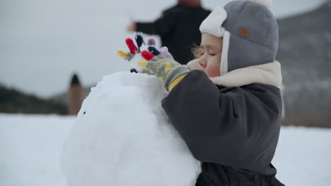 Multi-ethnic-Baby-Girl-Playing-An-Making-Big-Snowball-During-Winter