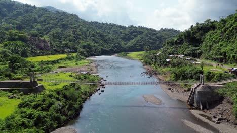 Suspension-bridge-spans-wide-river-in-Philippines-connecting-valley-sides-and-roads