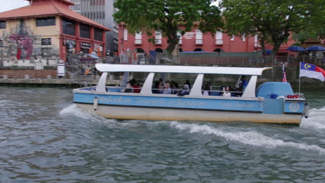 Tourists-enjoying-boat-ride-in-calm-waters-of-Malacca-River,panning-shot