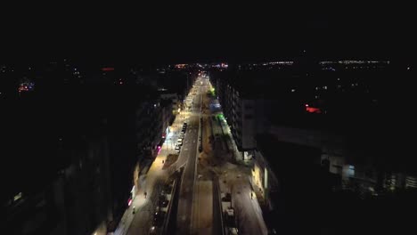 Aerial-drone-forward-moving-shot-over-the-city-center-at-night-with-illuminated-buildings-and-car-moving-in-Aveiro,-Portugal
