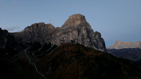 Spectacular-aerial-view-of-rugged-mountain-peaks-and-coniferous-woodlands-with-a-clear-sky-in-Val-Gardena-valley,-Dolomites