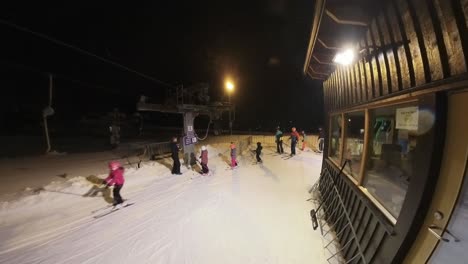 Children-hopping-on-to-ski-lift-during-evening-skiing-in-Myrkdalen-Norway---Static-clip-at-bottom-of-hill-ski-lift-station