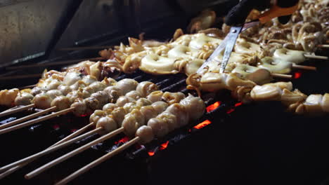 Close-up-clip-of-seafood-and-calamari-being-cooked-on-open-grill-at-streetfood-vendor's-stall