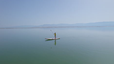 Lifeguard-on-a-standup-paddle-in-the-Dead-Sea-watching-over-bathers---parallax-shot