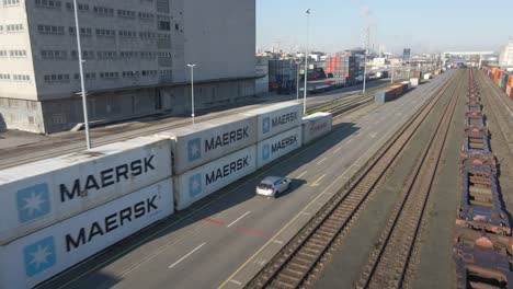 Drone-tracking-a-tourism-car-maneuvering-in-an-industrial-port-amidst-large-cargo-containers