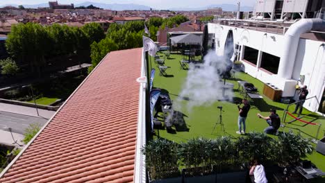A-DJ-mix-on-a-roof-top-he-releases-smoke,-the-wind-blows-and-in-the-background-Perpignan